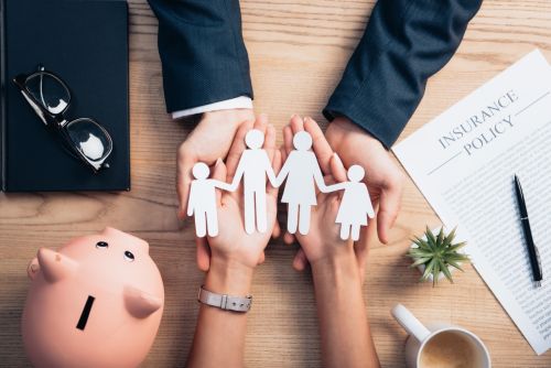 Top view of lawyer and woman holding paper cut family near cup of coffee, insurance policy agreement, piggy bank and plant - Concept for Family law lawyers.
