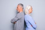 Elderly woman and man stand angrily back to back Concept for Gray Divorce.