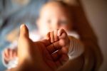 Parent's hand and holding newborn baby's hand,. Concept of Estate Planning for New Parents