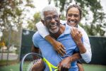 A senior black couple piggyback together on the tennis court. Concept for marriage tips.